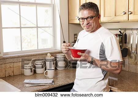 Stock Image - Hispanic man eating cereal. Fotosearch
