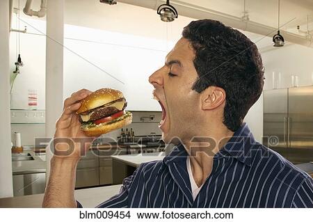 Hispanic man eating hamburger View Large Photo Image Picture - Hispanic man eating hamburger. Fotosearch