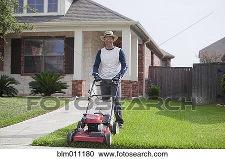 Stock Image - Hispanic man mowing his lawn. Fotosearch