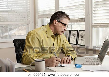 Stock Photography - Hispanic man paying bills at desk. Fotosearch