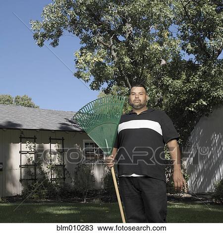 Hispanic man standing in yard with rake View Large Photo Image Stock Image - Hispanic man standing in yard with rake. Fotosearch