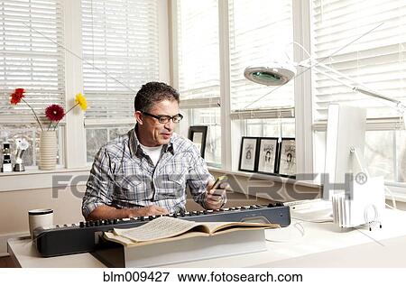 Stock Photo - Hispanic man with electronic keyboard and cell phone. Fotosearch