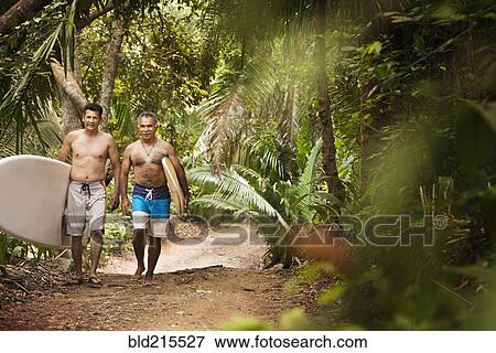 Hispanic men carrying surfboards on jungle trail View Large Photo Image Stock Photo - Hispanic men carrying surfboards on jungle trail. Fotosearch