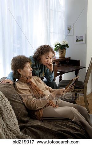 Stock Photo - Hispanic mother and daughter admiring picture frame. Fotosearch