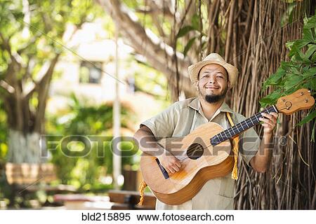Stock Photography - Hispanic musician playing guitar in park. Fotosearch