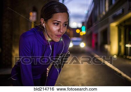 Hispanic runner resting on city street at night View Large Photo Image Stock Photograph - Hispanic runner resting on city street at night. Fotosearch