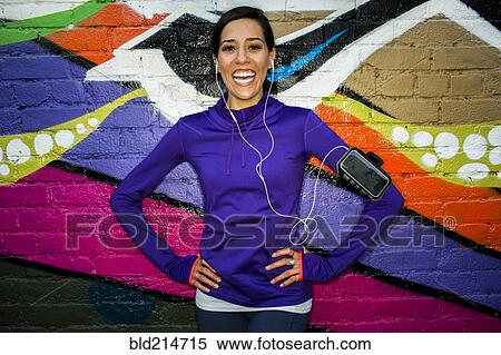Stock Photography - Hispanic runner smiling near graffiti wall. Fotosearch