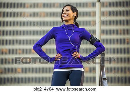 Picture - Hispanic runner standing near highrise building. Fotosearch