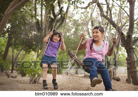 Hispanic sisters swinging on swings View Large Photo Image Stock Photo - Hispanic sisters swinging on swings. Fotosearch
