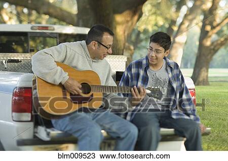 Hispanic son listening to father play guitar View Large Photo Image Stock Image - Hispanic son listening to father play guitar. Fotosearch