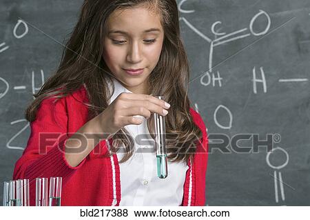 Stock Photo - Hispanic student examining test tube in science class. Fotosearch