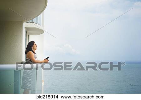 Hispanic woman admiring ocean from hotel balcony View Large Photo Image Picture - Hispanic woman admiring ocean from hotel balcony. Fotosearch