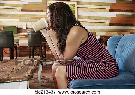 Stock Photo - Hispanic woman drinking coffee in cafe. Fotosearch