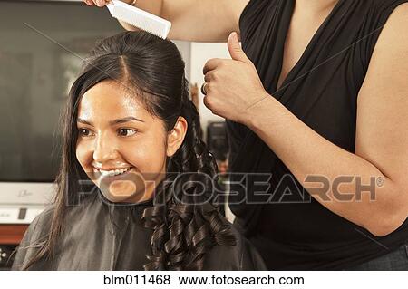 Stock Photo - Hispanic woman having hair styled in salon. Fotosearch