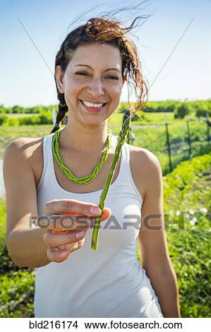 Picture - Hispanic woman holding asparagus in garden. Fotosearch