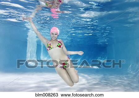 Stock Image - Hispanic woman in bikini swimming underwater. Fotosearch