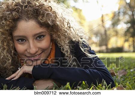 Stock Image - Hispanic woman laying in grass. Fotosearch