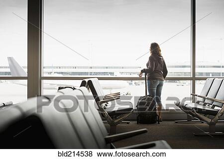 Hispanic woman looking out airport window View Large Photo Image Stock Photo - Hispanic woman looking out airport window. Fotosearch