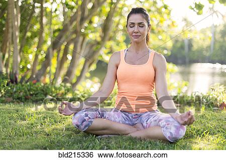 Stock Photograph - Hispanic woman meditating in park. Fotosearch