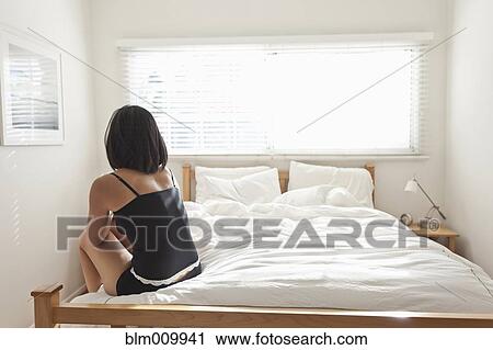 Hispanic woman sitting on bed View Large Photo Image Stock Image - Hispanic woman sitting on bed. Fotosearch