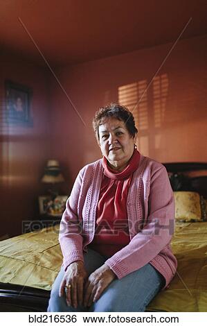 Hispanic woman sitting on bed View Large Photo Image Stock Photograph - Hispanic woman sitting on bed. Fotosearch