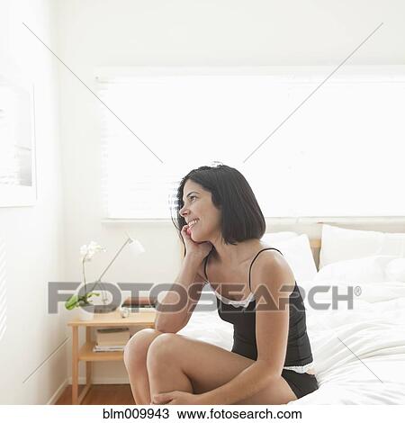 Hispanic woman sitting on bed talking on cell phone View Large Photo Image Stock Image - Hispanic woman sitting on bed talking on cell phone. Fotosearch
