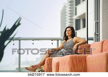 Stock Photo - Hispanic woman sitting on hotel balcony. Fotosearch