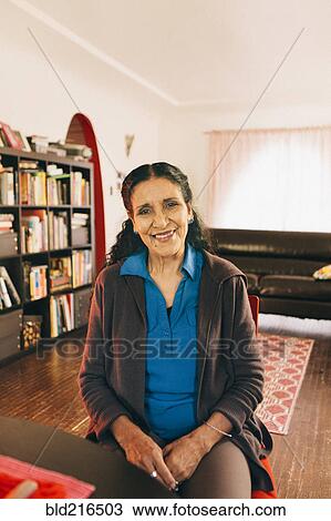 Stock Image - Hispanic woman smiling in living room. Fotosearch