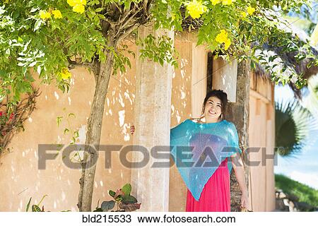 Stock Image - Hispanic woman smiling outside house. Fotosearch