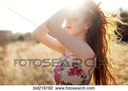 Stock Image - Hispanic woman standing in sunny field. Fotosearch