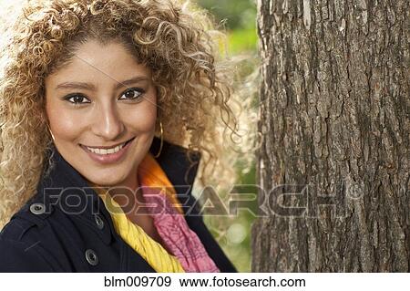 Stock Photo - Hispanic woman standing near tree. Fotosearch