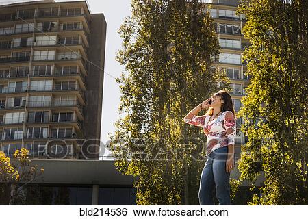 Hispanic woman talking on cell phone near trees View Large Photo Image Stock Photograph - Hispanic woman talking on cell phone near trees. Fotosearch