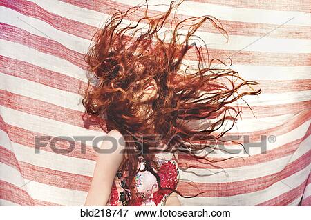 Stock Photo - Hispanic woman tossing her hair near striped sheet. Fotosearch