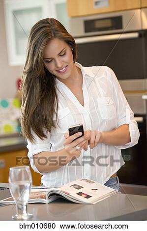 Hispanic woman using cell phone in kitchen View Large Photo Image Stock Image - Hispanic woman using cell phone in kitchen. Fotosearch