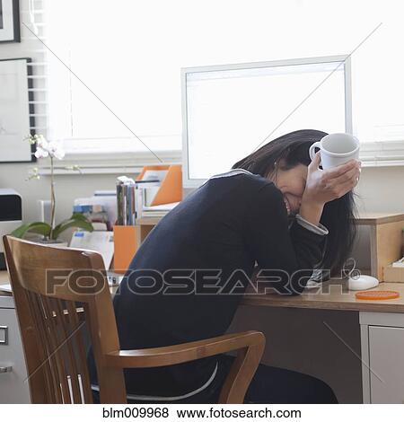 Stock Photo - Hispanic woman working in home office drinking coffee. Fotosearch
