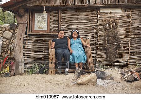 Stock Photo - Hispanic women sitting in front of house. Fotosearch