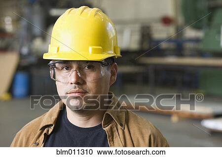 Stock Image - Hispanic worker in hard-hat and protective eyewear. Fotosearch