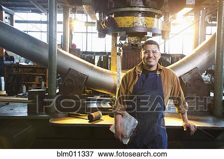 Hispanic worker standing in factory View Large Photo Image Stock Photo - Hispanic worker standing in factory. Fotosearch