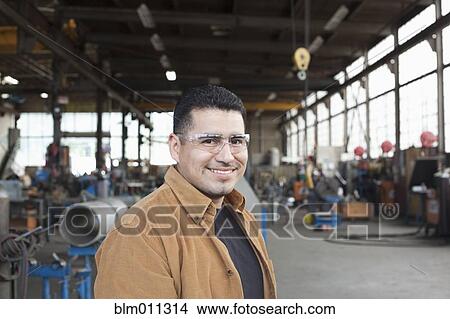 Hispanic worker standing in warehouse View Large Photo Image Picture - Hispanic worker standing in warehouse. Fotosearch
