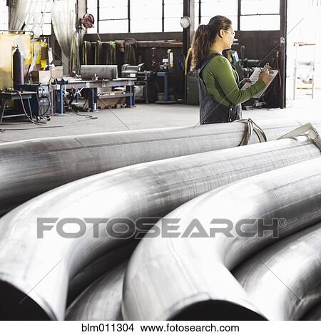 Hispanic worker standing near pipes in warehouse View Large Photo Image Picture - Hispanic worker standing near pipes in warehouse. Fotosearch
