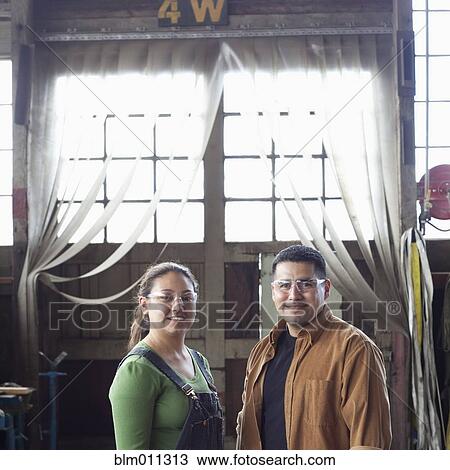 Stock Image - Hispanic workers standing in warehouse. Fotosearch
