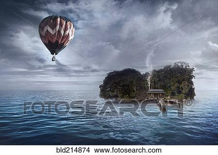 Picture - Hot air balloon floating over house on tropical island. Fotosearch