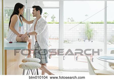 Picture - Husband smiling at wife sitting on counter. Fotosearch