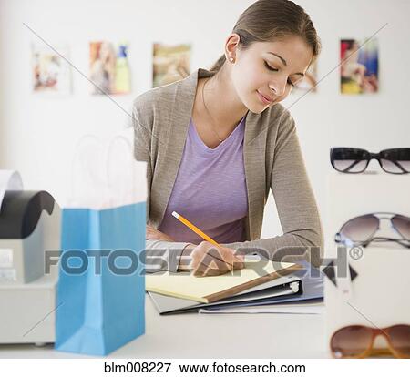 Stock Photo - Indian shop clerk writing on notepad in store. Fotosearch
