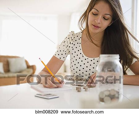 Indian woman counting coins and writing on notepad View Large Photo Image Stock Photo - Indian woman counting coins and writing on notepad. Fotosearch