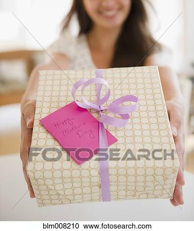 Stock Image - Indian woman holding out Mother's Day gift. Fotosearch
