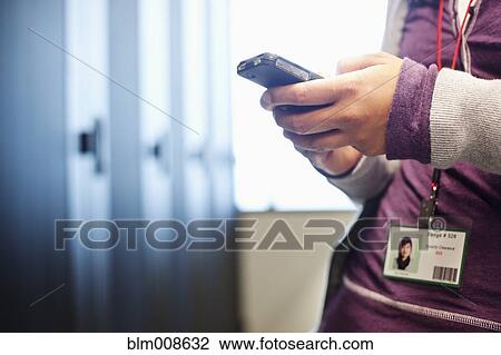 Stock Image - Japanese businesswoman using cell phone in office technology room. Fotosearch