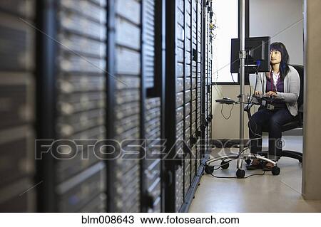 Stock Image - Japanese businesswoman working in office technology room. Fotosearch