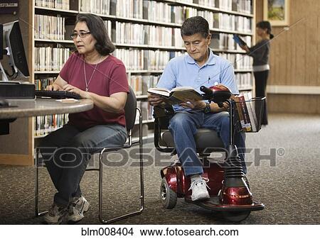 Japanese man in motorized scooter reading book in library View Large Photo Image Picture - Japanese man in motorized scooter reading book in library. Fotosearch