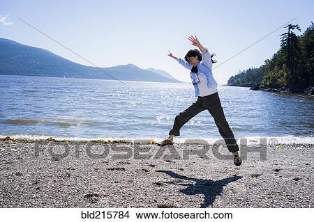Picture - Japanese woman doing cartwheel on beach. Fotosearch